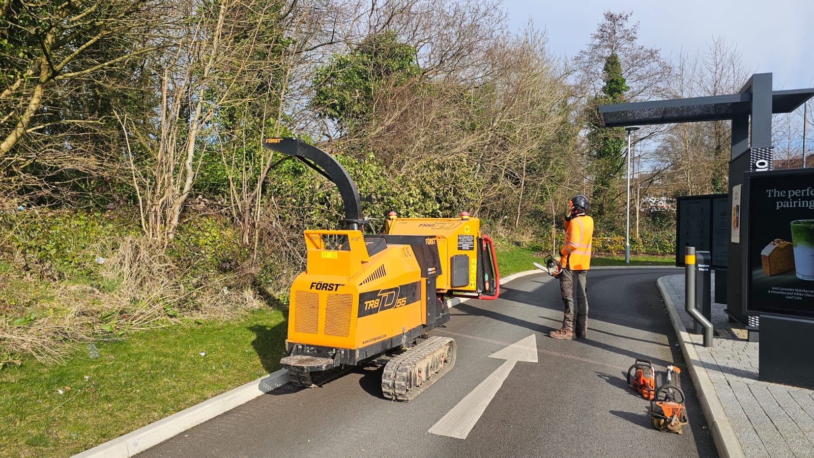 Professional tree surgeon with a Först wood chipper removing a storm-damaged tree at the Starbucks drive-through near Asda Clayton Brook.